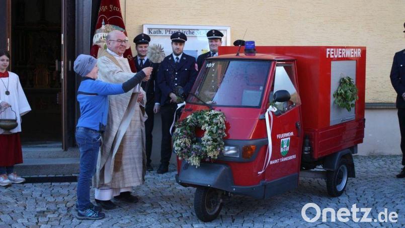 Pfarrer Wilhelm Bauer erteilt, unterstützt von Feuerwehrnachwuchskraft Felix Heuberger, der für Festumzüge umgebauten „Feuerwehr-Ape“ den kirchlichen Segen. Bild: Bernhard Zimmet/exb