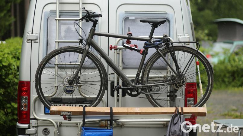 Ein Wohnmobil, an dem ein Fahrrad befestigt ist, steht auf einem Campingplatz. Vor Beginn der Pfingstferien bietet die Amberger Verkehrspolizei Tipps für Camper an und wiegt auch deren Fahrzeuge. Symbolbild: Matthias Bein/dpa