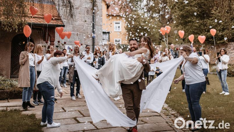 Sebastian Giering trägt seine Frau Maria durch ein Stoffherz. Mitgebracht hatten es Kolleginnen der Braut aus der kinderärztlichen Bereitschaftspraxis am Klinikum Weiden, die bis zuletzt nicht wussten, zu welcher Hochzeit es geht. Bild: www.julianbaecher.de