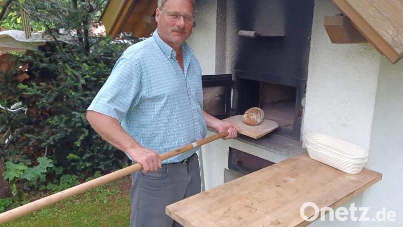 Ferdinand Raiml holt sein frisch gebackenes Brot aus dem selbstgebauten Ofen im Garten. Seit vielen Jahren frönt er dem Hobby Brotbacken und kennt inzwischen allerlei Tricks für gutes Gelingen. Bild: Annemarie Raiml/exb