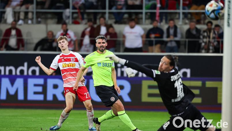 Der Regensburger Dominik Kother (links) trifft in dieser Szene gegen den Wiesbadener Torwart Florian Stritzel (rechts) zum 2:2 genau in den Torwinkel. Bild: Daniel Löb/dpa