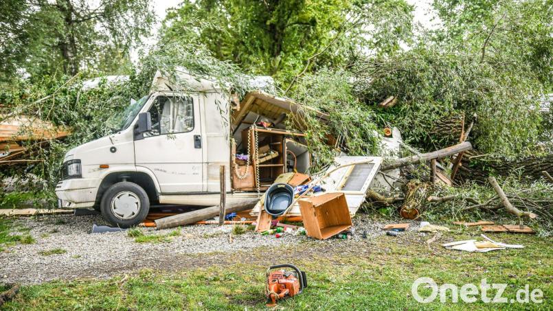 Umgestürzte Bäume und Äste liegen auf einem Wohnwagen auf einem Campingplatz in Lindau. Bild: Jason Tschepljakow/dpa