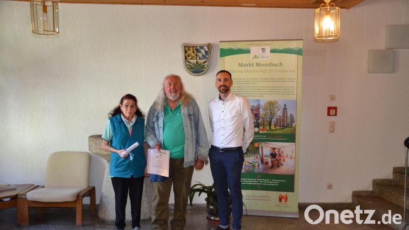 Für den 50. Aufenthalt in Moosbach dankt Bürgermeister Armin Bulenda (rechts) dem Urlaubsgast aus Kaiserslautern Lutz Cussnick mit seiner Lebensgefährtin und überreichte eine Urkunde mit Gutschein. Bild: gi