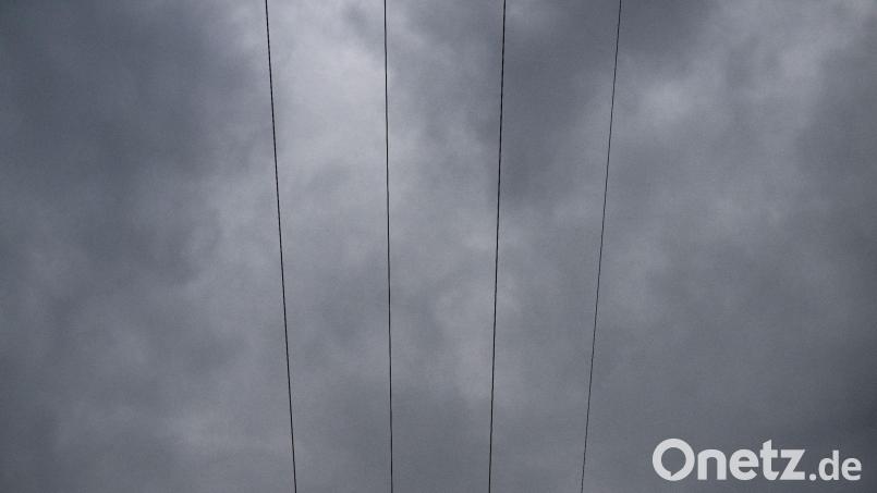Über den Leitungen eines Strommastes durchziehen Wolken den Himmel. Symbolbild: Pia Bayer/dpa