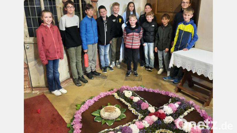 Die Firmlinge der Pfarrei Leonberg mit dem von ihnen gelegten Blumenteppich. Bild: Regina Grillmeier/exb
