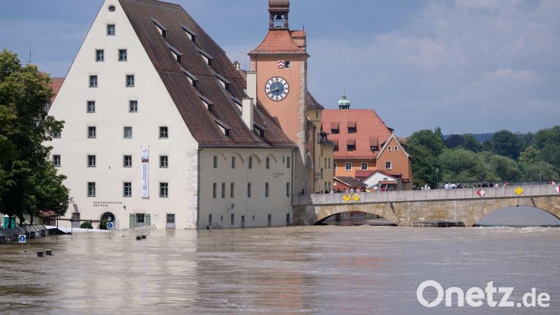 Menschen stehen in der Altstadt auf der Steinernen Brücke und schauen sich das Hochwasser an. Bild: Sven Hoppe/dpa