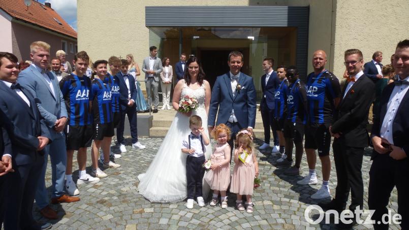 Christian und Annalena Bauer schreiten durch das Ehrenspalier der Fußballer ins Eheglück. Bild: bk
