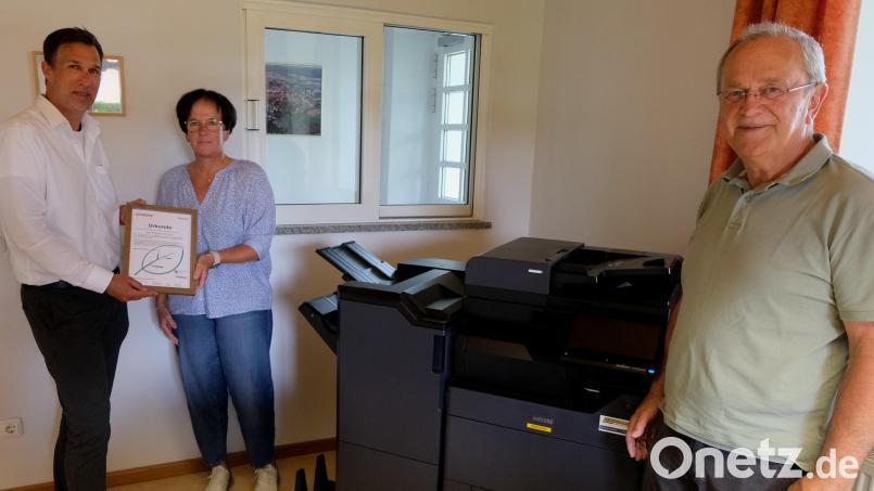 Mit einem neuen, nachhaltigen Drucker spart die Katholische Kirchenverwaltung in Floß ordentlich CO2 ein. Dafür gibt&#039;s sogar eine Urkunde, die Pfarrsekretärin Christine Sailer und Kirchenpfleger Josef Rosner (rechts) durch Andreas Kiebist für die Kirchenverwaltung in Empfang nehmen. Bild: le