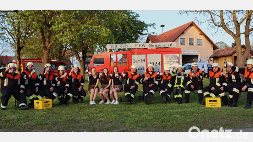 Die Jubiläumswehr lädt vor einem stilisierten Feuerwehrauto am Dorfplatz von Nunzenried zum 150-jährigen Gründungsfest ein. Bild: lg