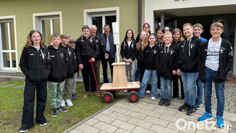 Im Beisein der Ministranten dankt Pfarrer Erwin Bauer (Sechster von links) dem leidenschaftlichen Schreiner Karl Schaller (rechts daneben) für sein Meisterstück: den Bollerwagen für den Lautsprecher. Bild: Karl Ziegler