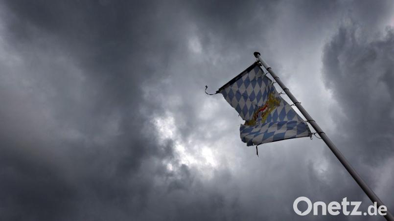 Eine Bayernfahne weht vor dichten Regenwolken im Wind. Bild: Karl-Josef Hildenbrand/dpa