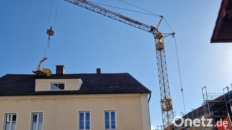 Ein Kran, der bei der Baustelle der Sparkasse (rechts) an der Postgartenstraße in Schwandorf benötigt wird, verursachte Mittwochabend Schaden am Dach des Nachbarhauses (links). Bild: td
