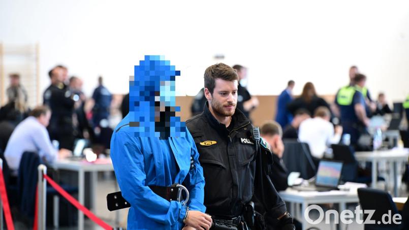 Einer der Angeklagten wird von einem Polizeibeamten in den Gerichtsaal gebracht. Bild: Udo Güldner