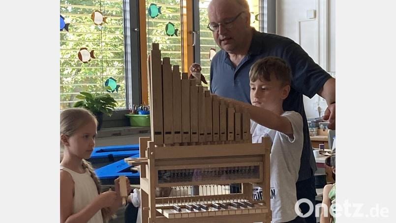 Organist Bernhard Müllers mit zwei Schülern beim Erforschen der kleinen Orgel. Bild: Michaela Meier/exb