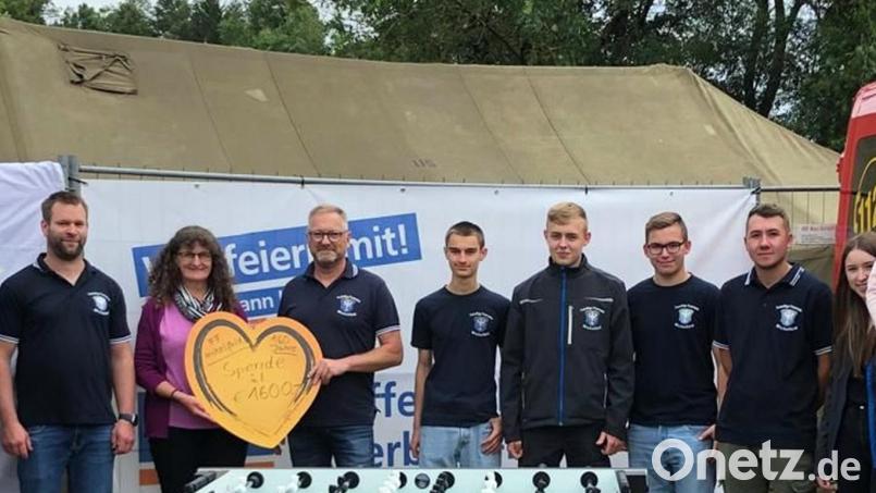 Raiffeisenbank-Geschäftsstellenleiterin Gerda Deinzer (Zweite von links) überreicht dem stellvertretenden Kommandanten Stefan Neukam (Dritter von links) den Scheck zum Feuerwehr-Jubiläum und den Kicker für die Jugend. Bild: jma