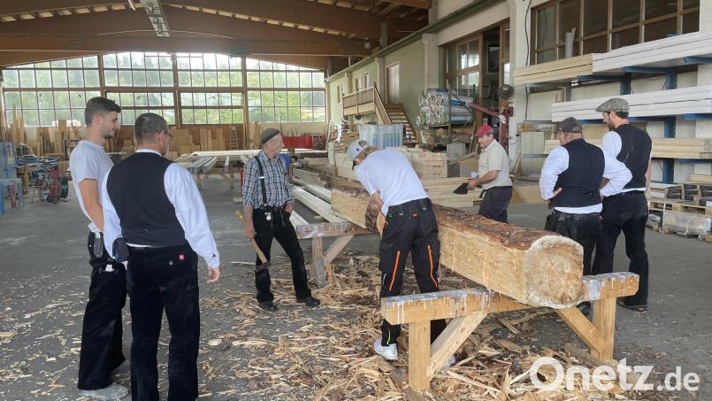 Die Mitglieder des Zimmerervereins Amberg lassen sich in Edelsfeld das traditionelle Behauen von Holzbalken vorführen. Bild: Michael Kohl/exb