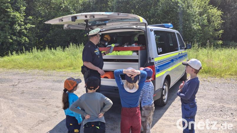 Polizeioberkommissar Carsten Landgraf von der Polizeiinspektion Kemnath zeigte den Kinder, was sich im Kofferraum eines Einsatzwagens befindet. Bild: Waldkindergarten "Die Goldbacher Wurzelzwerge"/exb