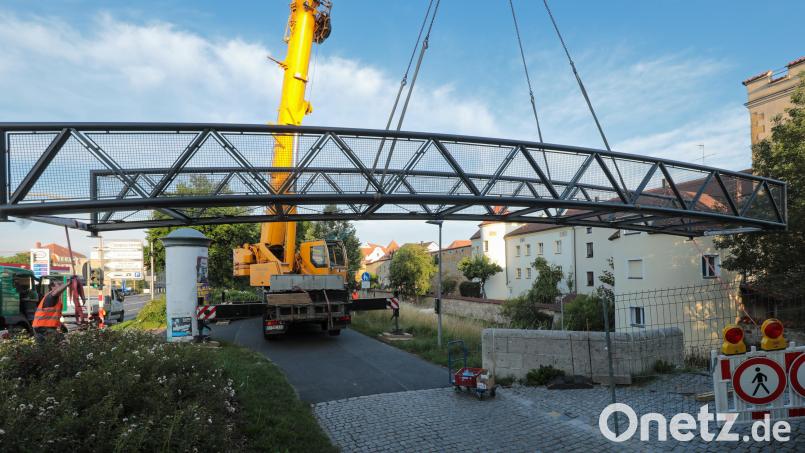 Der sanierte Basteisteg wird eingehoben. Seit dem frühen Mittwochmorgen ist der beliebte Fußgängersteg wieder in Amberg. Bild: Wolfgang Steinbacher
