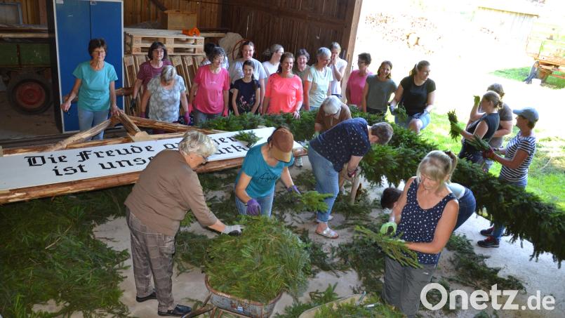 Mädchen und Frauen flechten mit Streu einen Triumphbogen zur Primiz von Neupriester Michael Steinhilber. Bild: gi