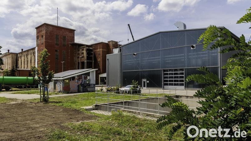 Neben der Schwandorfer Klärschlammtrocknungsanlage (rechts) läuft ein Bahngleis, auf dem gerade ein Zug mit grünen Müllcontainern rollt. Die roten Gebäude dahinter gehören bereits zur Nabaltec. Hier wäre eine möglicher Standort für eine Klärschlammverbrennung. Bild: Hösamer