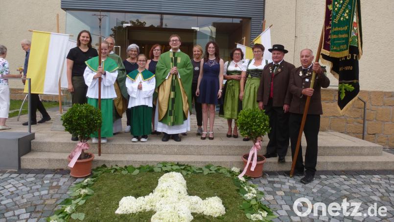 Einen Blumenteppich hat der Pfarrgemeinderat vor der St.-Martins-Kirche gelegt. Die Mitglieder übergeben symbolische Geschenke. Die Hubertus-Schützen freuen sich über das Fahnenband. Bild: Bock/exb