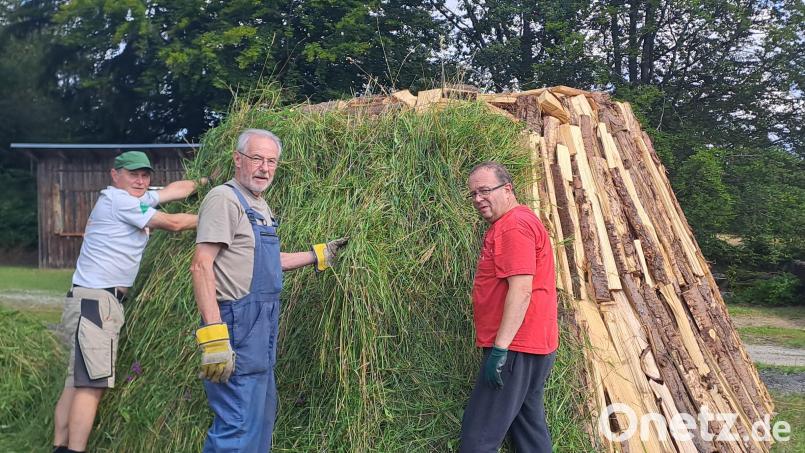 Mit den letzten Vorbereitungen sind die erfahrenen Meilerbrenner Alfons Klingel (Mitte) und seine Helfer Hans-Georg Braun (rechts) und Michael Daubner (links) beschäftigt. Der Meiler wird mit Gras ummantelt, die Kohlenlösche aufgebracht. Bild: gis