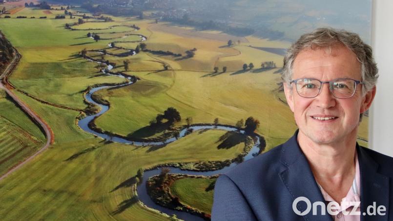 Franz Grabinger vor seinem Lieblingsfoto, das in seinem Bürgermeisterbüro hängt. Es zeigt das Schwarzachtal mit Blick auf seine Heimatgemeinde Schwarzach bei Nabburg (im Hintergrund). Bild: Thomas Dobler