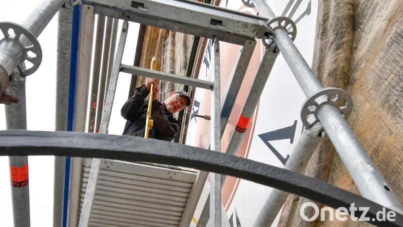 Steffen Dietz von der Firma Glockengießerei Perner aus Passau befestigt die Zeiger an den Turmuhren der St. Martinskirche in Amberg. Bild: Petra Hartl