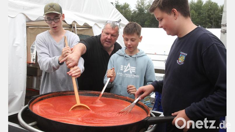 Küchenmeister Peter Beer leitet die Jugendlichen in der Feldküche an und unterstützt sie beim Rühren der Tomatensoße in der Gusspfanne. Bild: Hirsch