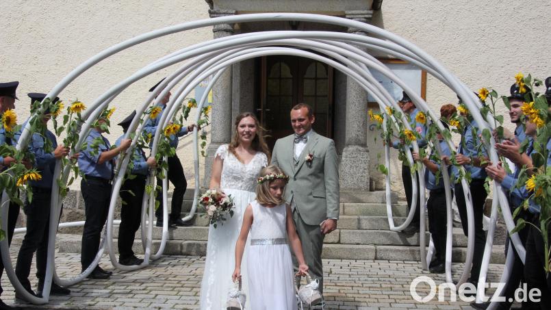 Freudestrahlend verlassen Alexandra und Andreas Fischer und das Brautmädchen Luise die Pfarrkirche in Großkonreuth. Sie werden von der Feuerwehr Großkonreuth erwartet. Bild: kro
