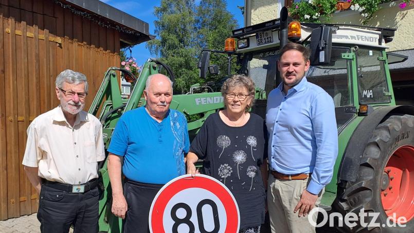 Jubilar Bernhard Sauer vor einem großen Traktor mit Ehefrau Brigitta, Bürgermeister Sebastian Voit (rechts) und Manfred Prechtl (links), einem langjährigen Freund aus Mehlmeisel. Bild: gis