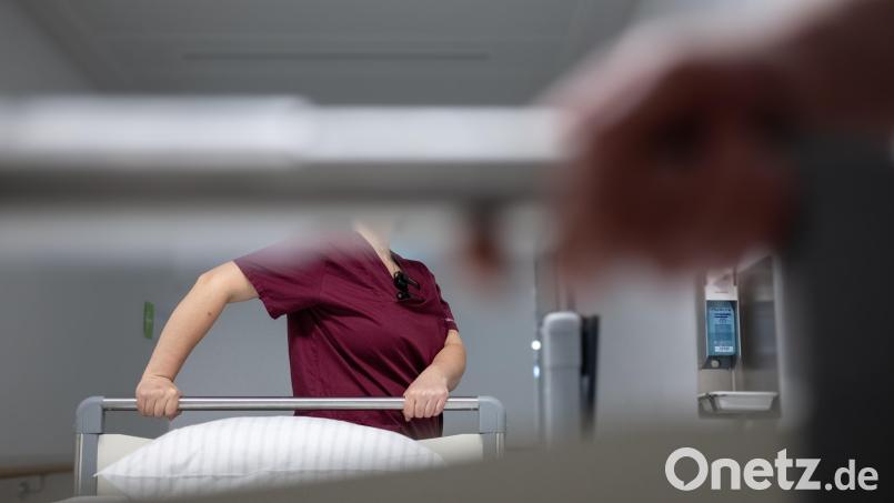 Eine Krankenpflegerin schiebt ein Krankenbett durch den Gang einer Station eines Krankenhauses. Symbolbild: Marijan Murat/dpa