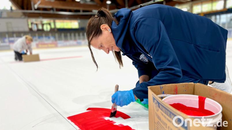 Sandra Häberl vom Blue Devils-Fanshop malt die Markierungen auf die Eisfläche im Weidener Eisstadion. Im Hintergrund ist ihre Kollegin Nicole Schenke zu sehen. Bild: Gabi Schönberger