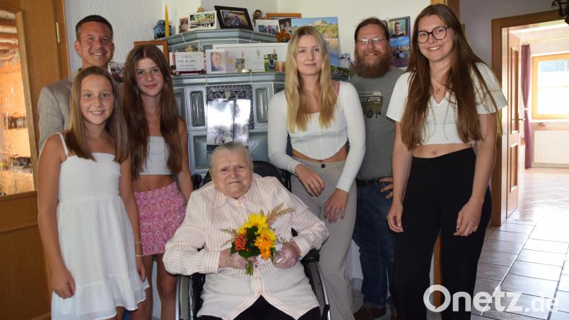 Zu deren 100. Geburtstag versammeln sich (stehend, von links) Emily, Luisa, Emma und Celina um ihre Uroma Anna Lederer. Auch Bürgermeister Jörk Kaduk (hinten links) und Diakon Bernd Deyerl (hinten rechts) gratulieren. Bild: hdk