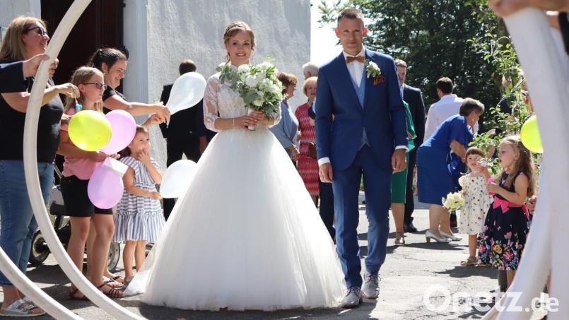 Daniela und Matthias Schmid durchschreiten nach ihrer kirchlichen Trauung auf dem Fahrenberg bei Waldthurn ein Spalier der Feuerwehr Spielberg. Bild: Theresa Schwab/exb