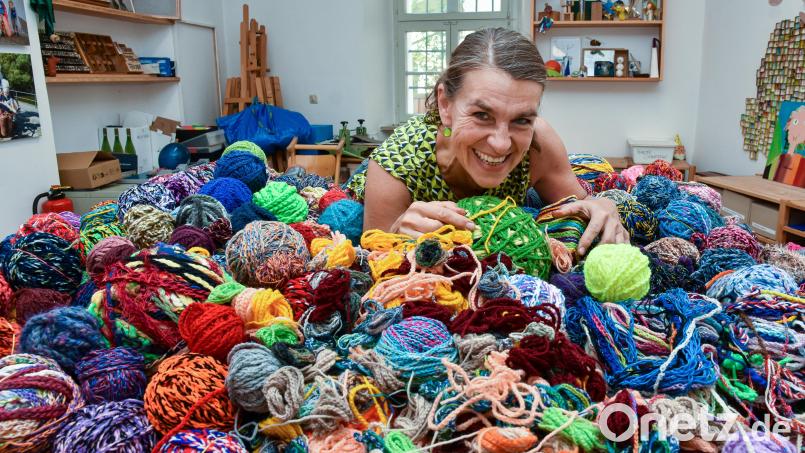 Michaela Peter, eine der Luftlehrerinnen im Luftmuseum in Amberg, präsentiert einen ganzen Berg kunterbunter Luftmaschenschnüre und -knäuel, die Kreative im Luftmuseum abgegeben haben. Bild: Stephan Huber