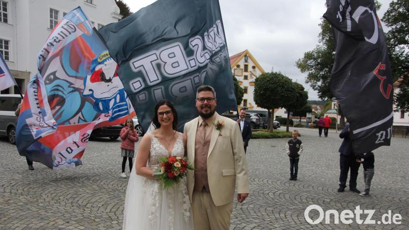 Jessica und Nico Bergauer vor den wehenden Fahnen des Selber-Wölfe-Fanclubs „Fanatics 2003“, dessen Vorsitzender der Bräutigam ist. Bild: kro