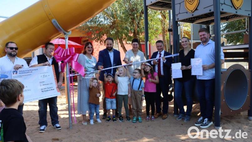 Die Kinder schneiden gemeinsam mit Oberbürgermeister Jens Meyer (Dritter von rechts) das Band zur offiziellen Eröffnung des neuen Spielgerätes durch. Ermöglicht wurde dieses durch Spenden. Bild: Peter Schörner/exb