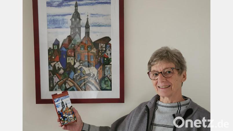 Bärbel Eichenmüller vom Weltladen-Team mit der neuen Auerbach-Schokolade vor dem Bild, das Sr. Liselotte Schuhmann gemalt und als Motiv für die Tafel zur Verfügung gestellt hat. Bild: Martina Heberl/exb