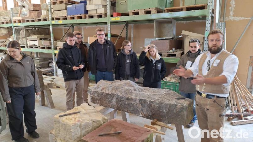 Ausbildungsmeister Maximilian Meinel erklärt den angehenden Architekten, auf was sie achten müssen, wenn sie jetzt selbst einmal einen Stein bearbeiten dürfen. Bild: Alexandra Hautmann/fph