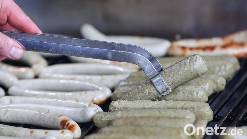 Bratwürste aus Fleisch (links) und vegane Bratwürste (rechts) liegen nebeneinander auf dem Holzkohlengrill. Auf dem Christkindlesmarkt in Nürnberg soll es heuer mehr vegane Angebote geben. Symbolbild: Daniel Löb /dpa