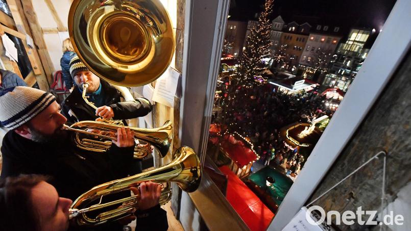 Blasmusiker spielen für die Besucherinnen und Besucher eines Weihnachtsmarktes. Symbolbild: Martin Schutt/dpa
