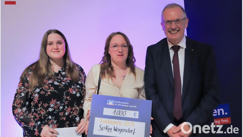 Die Gardetrainerinnen (von links) Ivonne Walter und Samantha Müller nehmen den symbolischen Scheck von Raiffeisen-Vorstandsmitglied Bernd Strauß entgegen. Bild: Raiffeisenbank Nürnberger Land