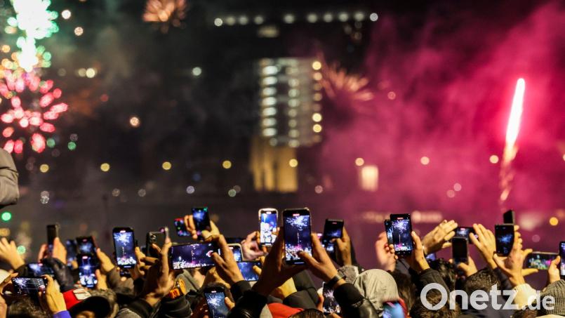 Silvester in Düsseldorf - und Tausende Menschen am Rheinufer filmen mit. Bild: Christoph Reichwein/dpa