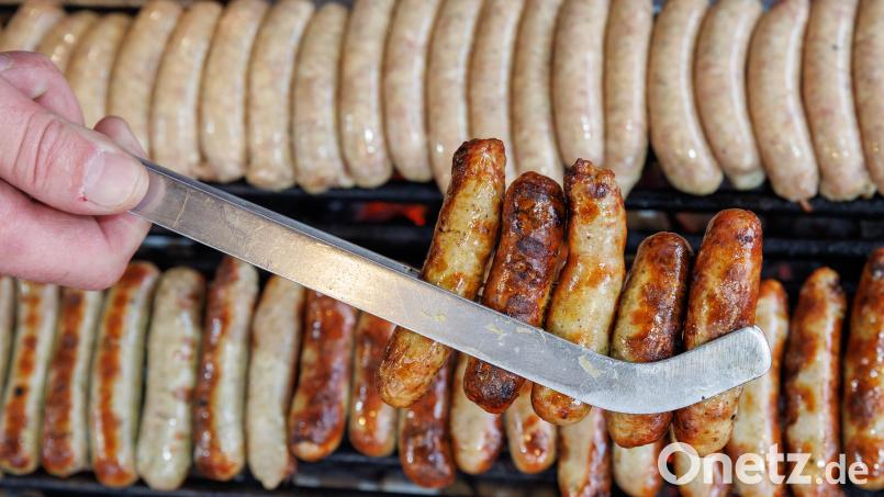 Nürnberger Rostbratwürste liegen in einer Zange auf dem Nürnberger Christkindlesmarkt. Symbolbild: Daniel Karmann/dpa