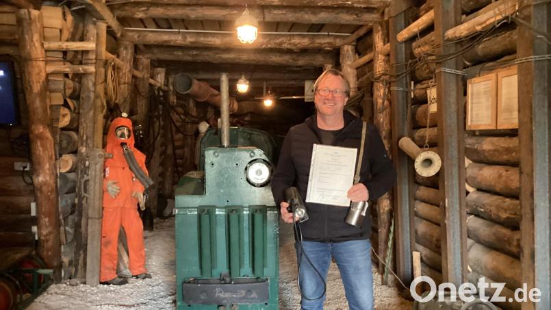 Matthias Regn im Auerbacher Schaustollen mit seinem Zeugnis und einer Grubenlampe in der rechten sowie einem Selbstretter in der linken Hand. Die beiden Geräte mussten immer am Mann getragen werden. Bild: mzi