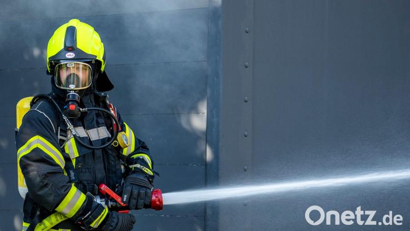 Mit Atemschutz löschte die Weidener Feuerwehr den Brand in einem grünen Container in der Müllumladestation. Symbolbild: David Inderlied/dpa