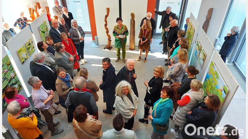 Zahlreiche Besucher lassen sich am Marktsonntag die Eröffnung der Kunstausstellung mit Blumengemälden und Holzskulpturen nicht entgehen. Bild: Georg Lang/exb