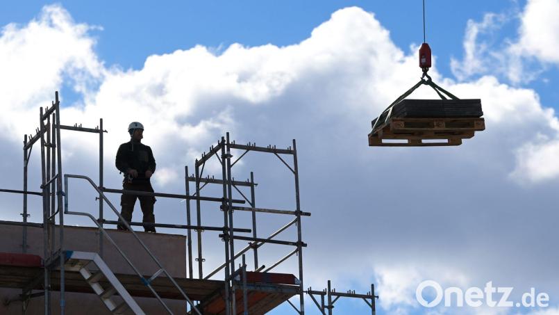 Ein Arbeiter dirigiert auf einer Baustelle einen Kran. Die Saison in den Außenberufen beginnt wieder. Das macht sich bei den Arbeitslosenzahlen bemerkbar. Bild: Soeren Stache/dpa-Zentralbild/dpa/Archivbild