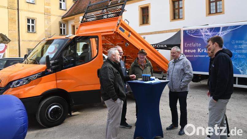 Martin Kopp, ZEN-Geschäftsführer und Klimaschutzmanager des Landkreises Amberg-Sulzbach (links), im Gespräch mit interessierten Ausstellungsbesuchern. Dahinter der orange Iveco-Kleinlaster, unter dessen hochgeklappter Ladefläche der massive Batterieblock verbaut ist. Bild: gf